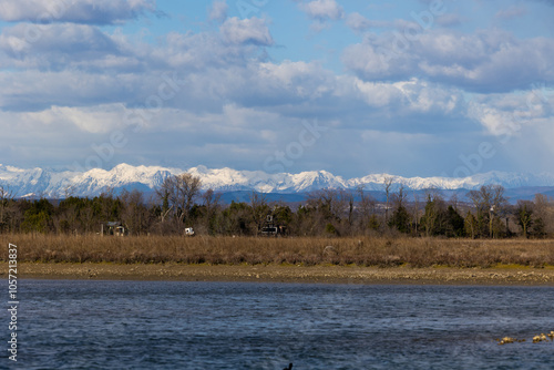 Obraz na płótnie ambiente naturale nel nord Italia, che si estende da un'area di palude fluviale sul mare fino alle catene montuose innevate lontane, con cielo nuvoloso, in inverno w salonie