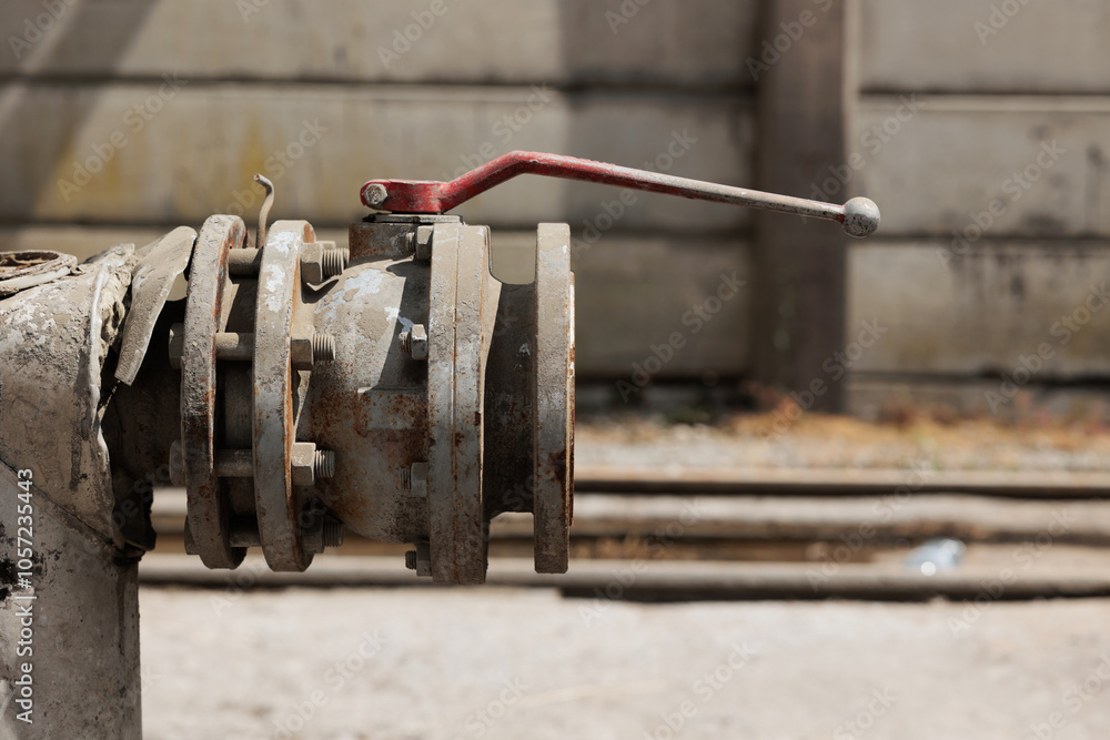 dettaglio di una valvola su una grossa tubatura per la regolazione del flusso di liquidi industriali, all'aperto, di giorno