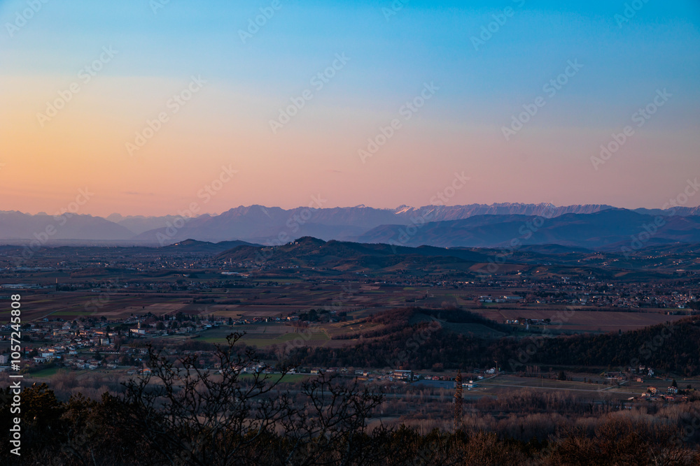 Fototapeta premium vista di parte del territorio della regione Friuli Venezia Giulia che si estende dai paesi vicino a Gorizia fino alle Alpi Giulie lontane, al tramonto, in autunno
