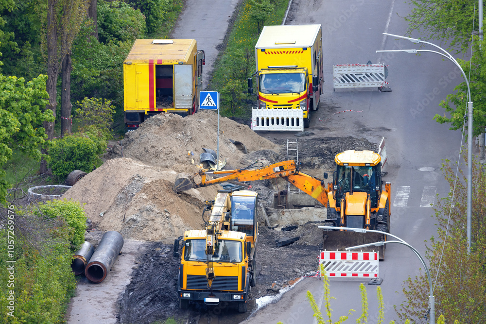 Road works with heavy machinery repairing a pipeline on a city street.