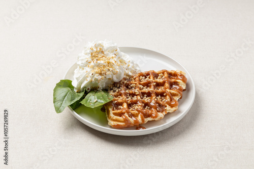 Croffle with whipped cream, basil leaves and caramel on a white plate. A trendy dessert or breakfast.