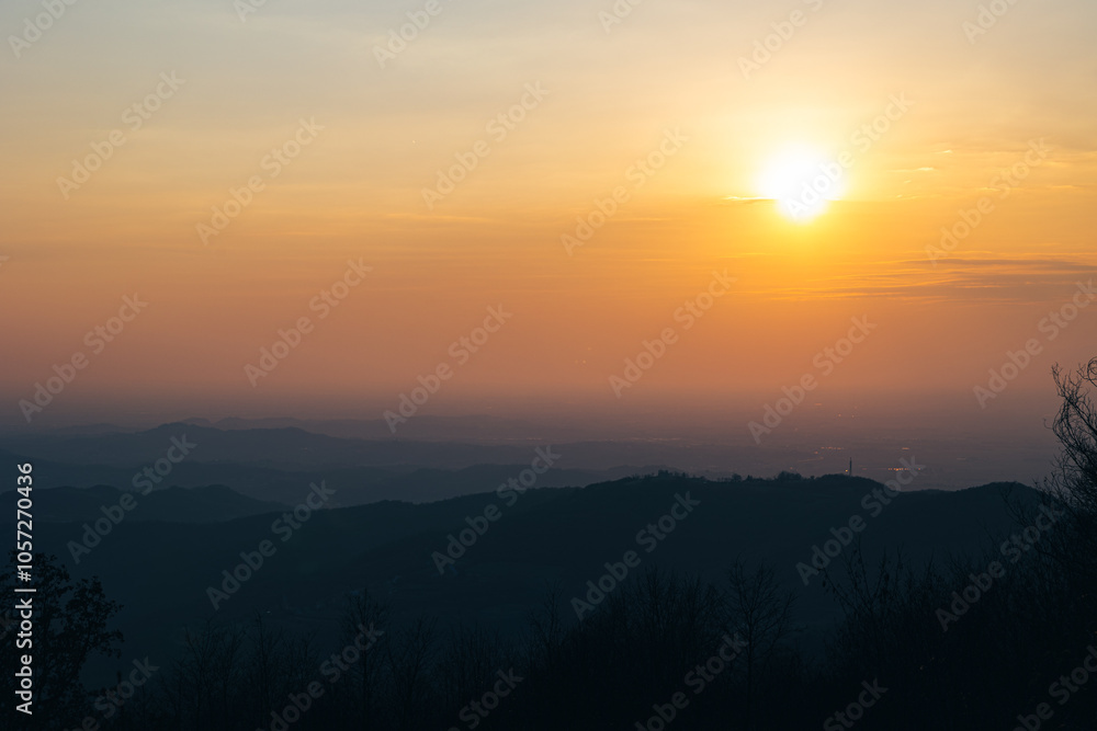 sole che tramonta all'orizzonte, dietro ad un fitto ammasso di nuvole e alla nebbia, colorata di sfumature di arancione, vista un ambiente tra pianura e collina tra Slovenia ed Italia sole che tramonta all'orizzonte, dietro ad un fitto ammasso di nuvole e alla nebbia, colorata di sfumature di arancione, vista un ambiente tra pianura e collina tra Slovenia ed Italia