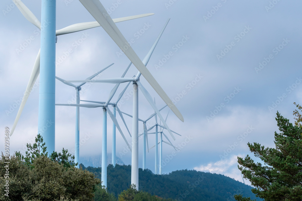 A striking close-up view of several wind turbines extending into the sky, showcasing their impressive blades and structural engineering in a green energy setting in Navarra Spain A striking close-up view of several wind turbines extending into the sky, showcasing their impressive blades and structural engineering in a green energy setting in Navarra Spain