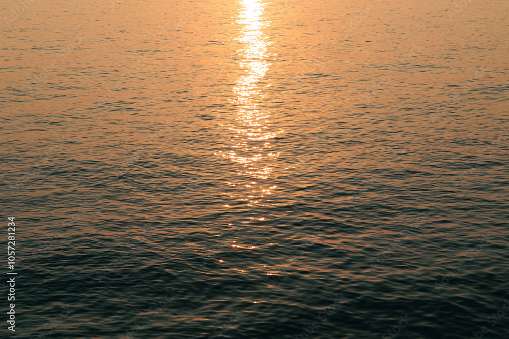 luce arancione del sole al tramonto che si riflette sulla superficie blu scuro del mare calmo luce arancione del sole al tramonto che si riflette sulla superficie blu scuro del mare calmo