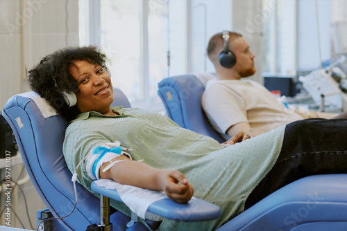 Photography African American woman and Caucasian man donating blood while relaxing in reclining chairs