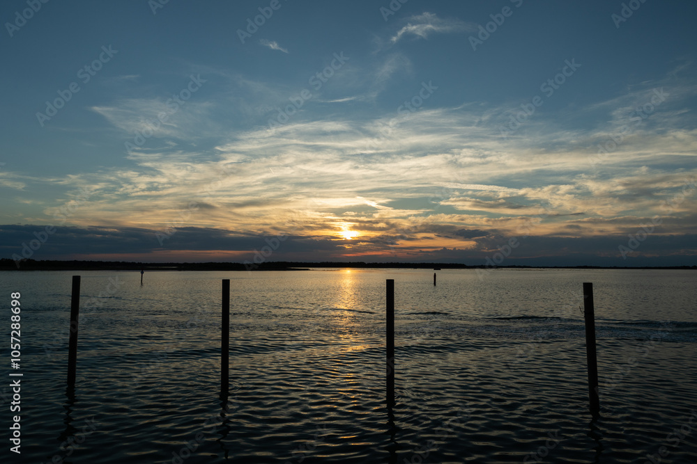 sole che tramonta sul mare calmo, all'orizzonte, dietro alle nuvole che coprono il cielo, in veneto, in estate sole che tramonta sul mare calmo, all'orizzonte, dietro alle nuvole che coprono il cielo, in veneto, in estate
