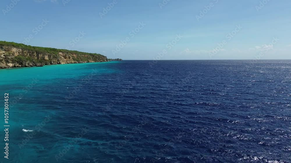 Beautiful Caribbean sea coast landscape with deep blue ocean water crashing on the rocks and cliffs and making waves on the sunny tropical island of Curacao - aerial drone flight shot Beautiful Caribbean sea coast landscape with deep blue ocean water crashing on the rocks and cliffs and making waves on the sunny tropical island of Curacao - aerial drone flight shot