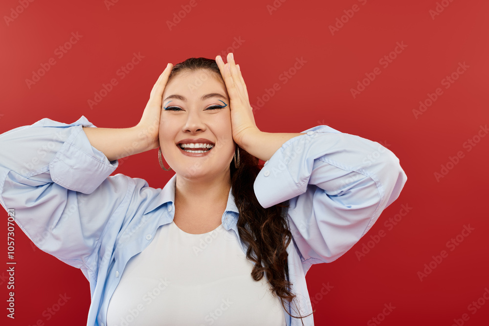 A young, beautiful plus size woman beams with happiness while showcasing her vivid makeup in a studio setting. A young, beautiful plus size woman beams with happiness while showcasing her vivid makeup in a studio setting.