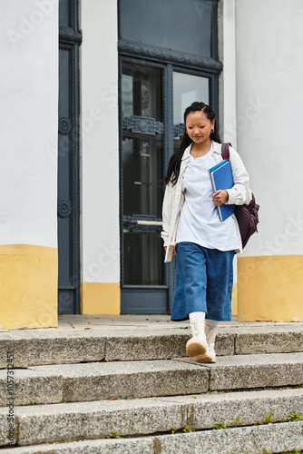 A young woman in trendy attire descends the university steps, radiating confidence and capturing youth culture.