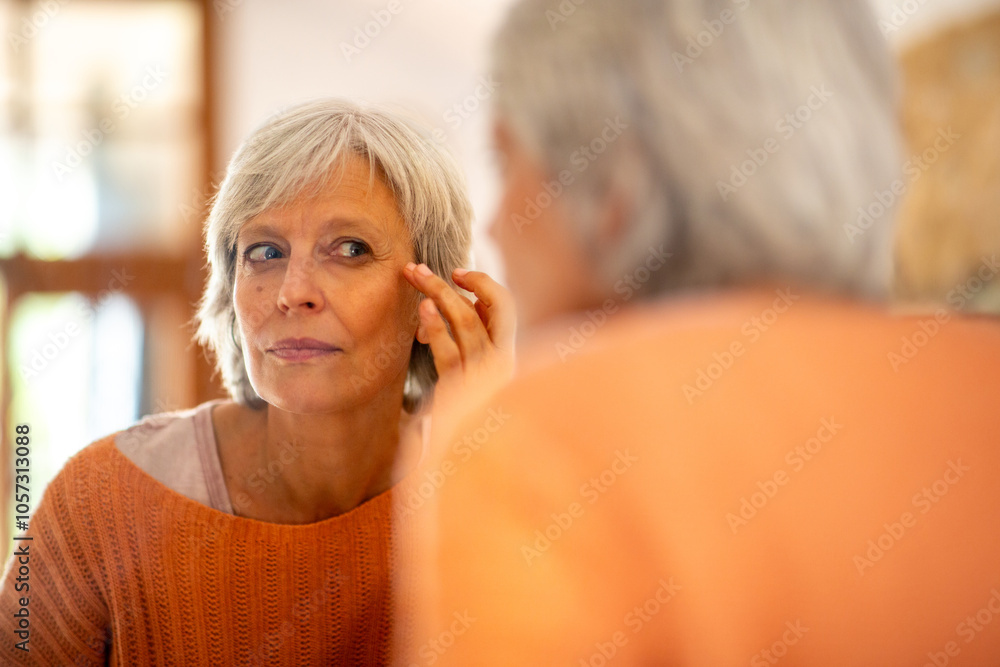 Mature woman doing facial skincare in front of mirror Mature woman doing facial skincare in front of mirror