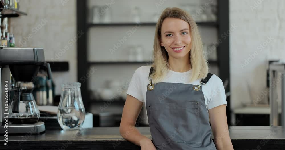 Beautiful female barista is happy smile in coffee shop bar. Portrait of happy employee behind cozy loft-style cafe counter in restaurant. Beautiful female barista is happy smile in coffee shop bar. Portrait of happy employee behind cozy loft-style cafe counter in restaurant.
