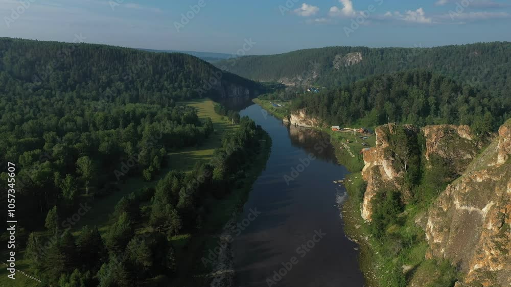 Sunlight illuminating a meandering river flowing through a valley with steep cliffs and lush green forest Sunlight illuminating a meandering river flowing through a valley with steep cliffs and lush green forest