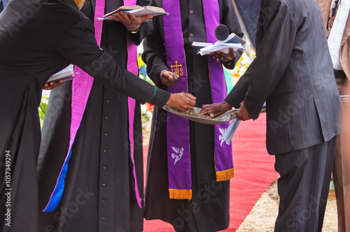 four priest and mourner holding a shovel spade with ground to bless the grave photo