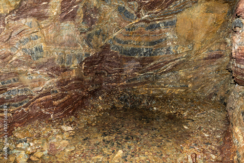 scavo dentro ad una grotta naturale con vista sulle varie stratificazioni antiche e naturali del terreno roccioso dai vari colori di rosso, arancione, marrone e grigio photo