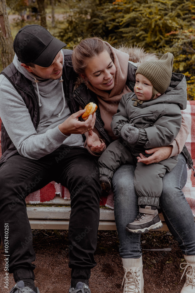 Family in park on bench with a child eating donuts and laughing Family in park on bench with a child eating donuts and laughing