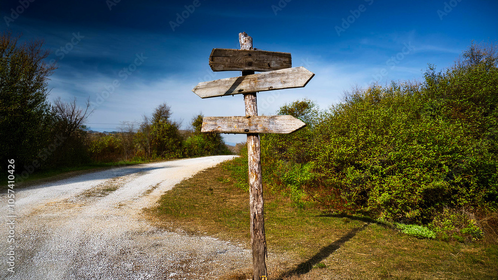 An old wooden road sign stands next to an old dirt road. An old wooden road sign stands next to an old dirt road.