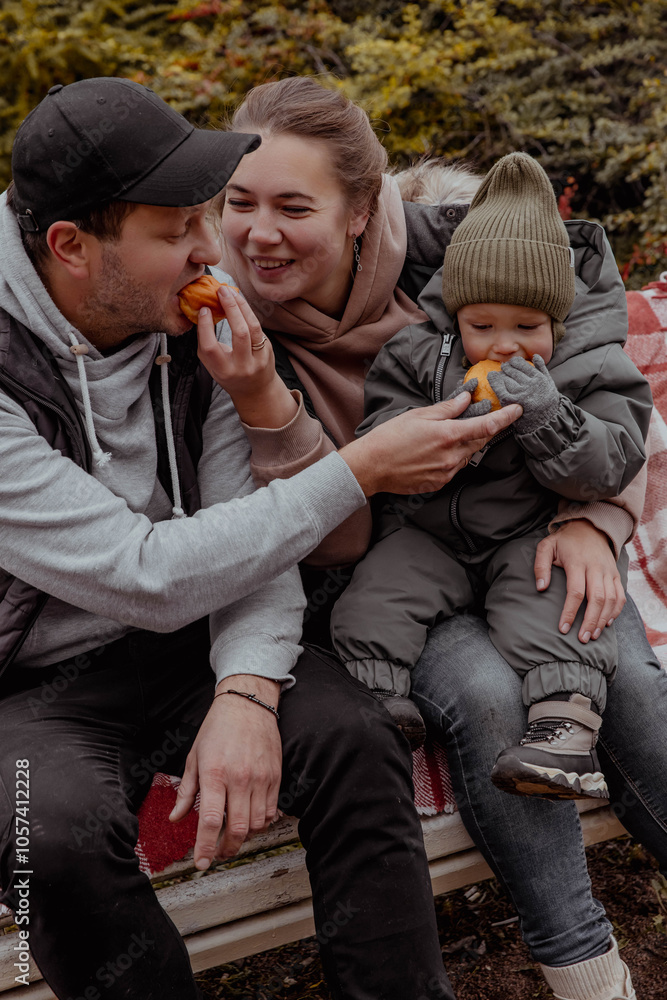 Family in park on bench with a child eating donuts and laughing Family in park on bench with a child eating donuts and laughing