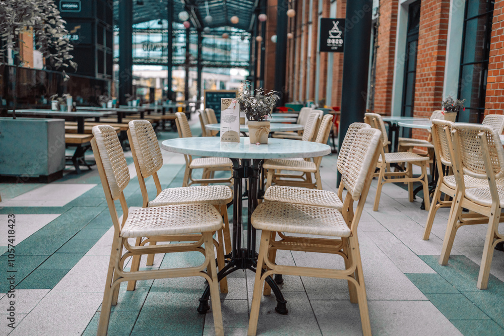 Naklejka premium Wooden chairs with a green flowers in the middle of the table of an outdoor restarurant. High quality photo