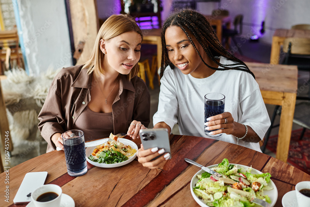 A smiling couple enjoys a meal at a charming cafe, capturing a special moment on their phone.
