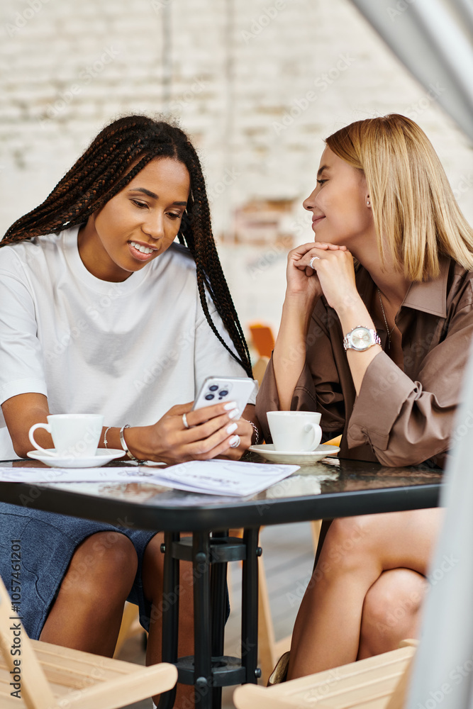 A cheerful multiethnic lesbian couple shares a tender moment while enjoying coffee and smiles at a cafe. A cheerful multiethnic lesbian couple shares a tender moment while enjoying coffee and smiles at a cafe.