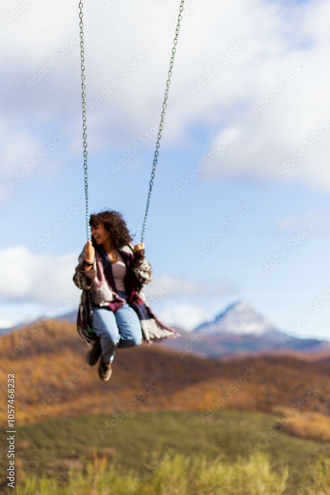 Young woman swinging on the giant swing in Riaño, León, Spain, surrounded by a stunning backdrop of the 'Fiords of León.' As she swings out over the breathtaking landscape, vast mountains and the calm Young woman swinging on the giant swing in Riaño, León, Spain, surrounded by a stunning backdrop of the 'Fiords of León.' As she swings out over the breathtaking landscape, vast mountains and the calm