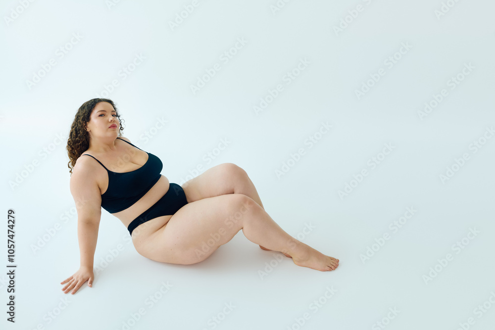 A confident plus size woman showcases her beauty while seated gracefully, exuding self love. A confident plus size woman showcases her beauty while seated gracefully, exuding self love.