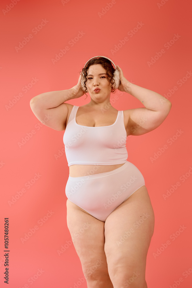 A plus size woman poses joyfully against a bright pink backdrop, exuding confidence and style. A plus size woman poses joyfully against a bright pink backdrop, exuding confidence and style.