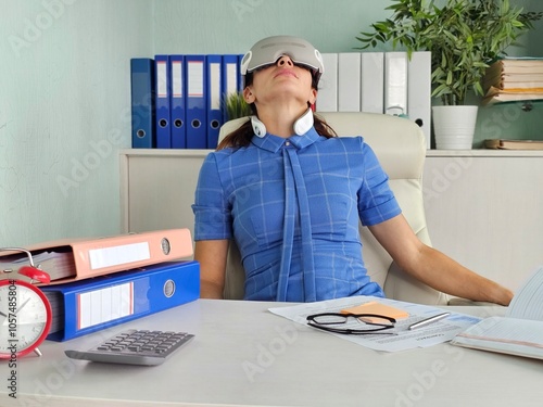 Fotografie Woman relaxing with eye and neck massager at work place in office