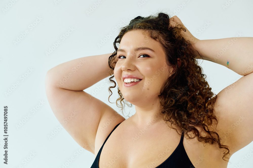 A radiant plus size woman with curly hair smiles warmly while playfully posing with her hands. A radiant plus size woman with curly hair smiles warmly while playfully posing with her hands.