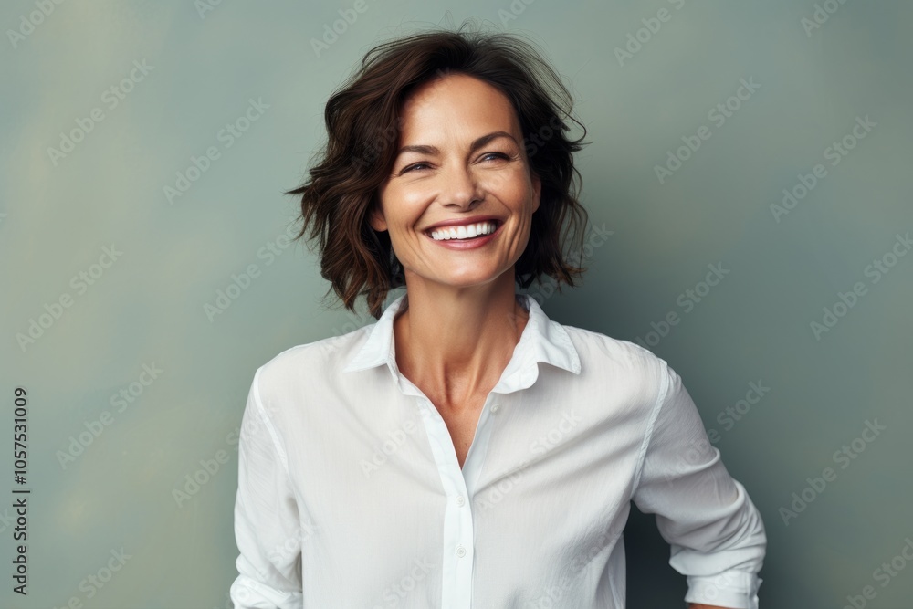 Portrait of a satisfied woman in her 40s wearing a simple cotton shirt on blank studio backdrop Portrait of a satisfied woman in her 40s wearing a simple cotton shirt on blank studio backdrop