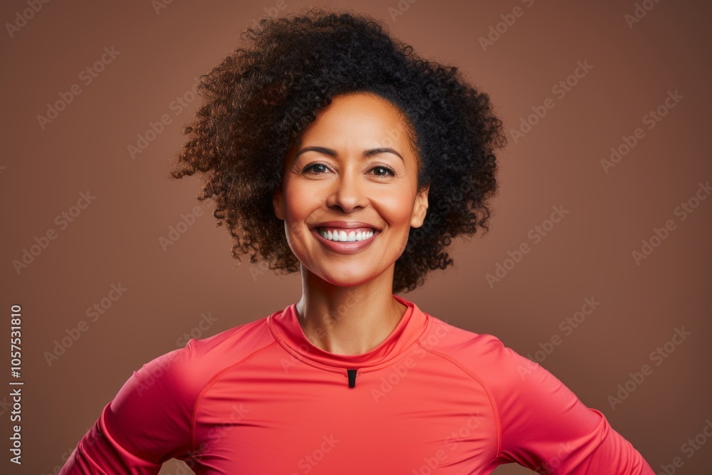 Portrait of a content afro-american woman in her 40s wearing a moisture-wicking running shirt on blank studio backdrop Portrait of a content afro-american woman in her 40s wearing a moisture-wicking running shirt on blank studio backdrop