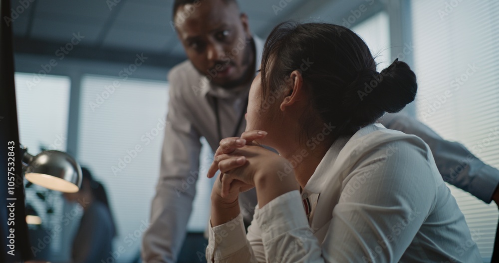 Call center office: Close up of tired Asian female helpdesk specialist holding head, feeling stressed. African American employee supports colleague. Mental health hotline. Online customer service. Call center office: Close up of tired Asian female helpdesk specialist holding head, feeling stressed. African American employee supports colleague. Mental health hotline. Online customer service.