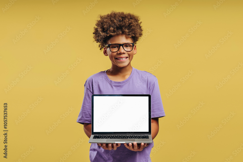 Smiling, positive African American boy wearing stylish eyeglasses, holding laptop with empty screen Smiling, positive African American boy wearing stylish eyeglasses, holding laptop with empty screen