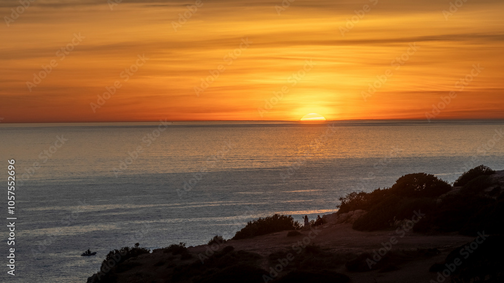 Vibrant golden sky at sunset viewed from Benagil Beach along the coast of Portugal; Lagoa, Faro, Portugal Vibrant golden sky at sunset viewed from Benagil Beach along the coast of Portugal; Lagoa, Faro, Portugal