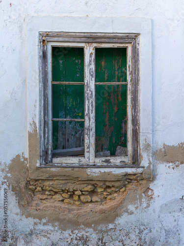 Close-up of a weathered and boarded up wooden window frame and wall with peeling paint; Lagos, Faro, Portugal