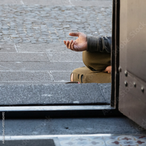 Beggar sits outside a doorway holding out their hand; Camara de Lobos, Madeira, Portugal photo