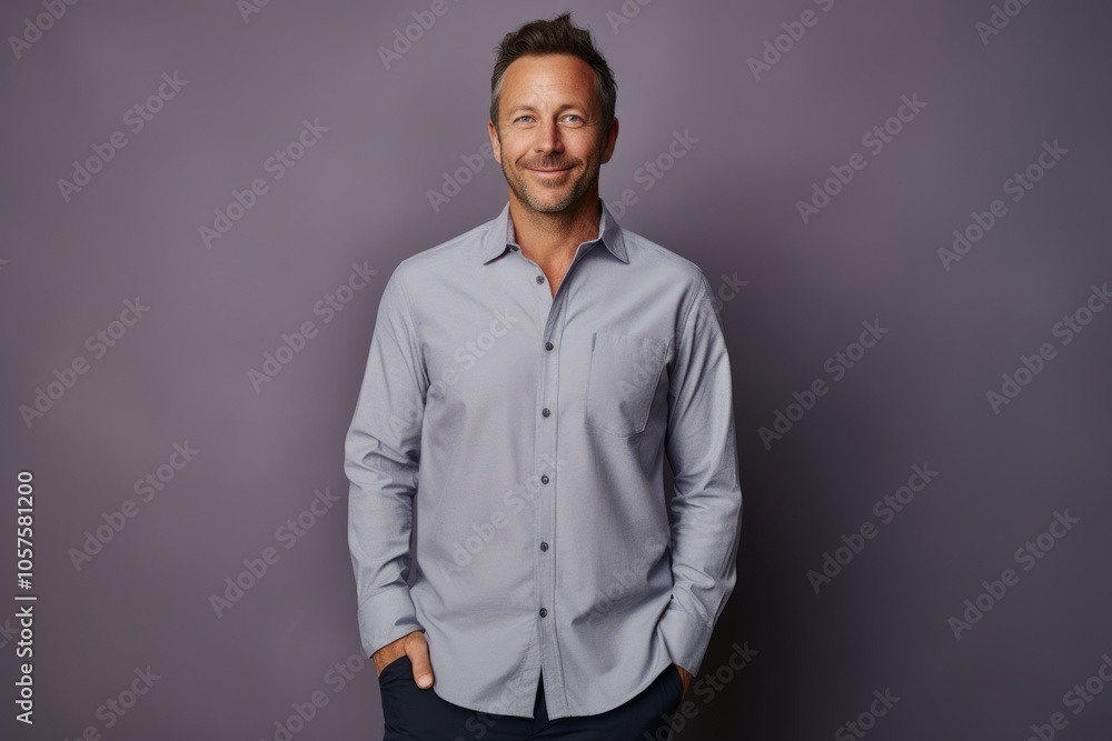 Obraz premium Portrait of a glad man in his 40s showing off a lightweight base layer isolated in plain cyclorama studio wall