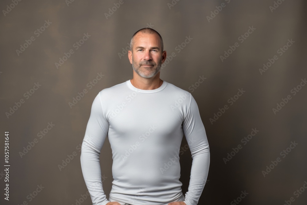 Obraz premium Portrait of a glad man in his 40s showing off a lightweight base layer in front of plain cyclorama studio wall