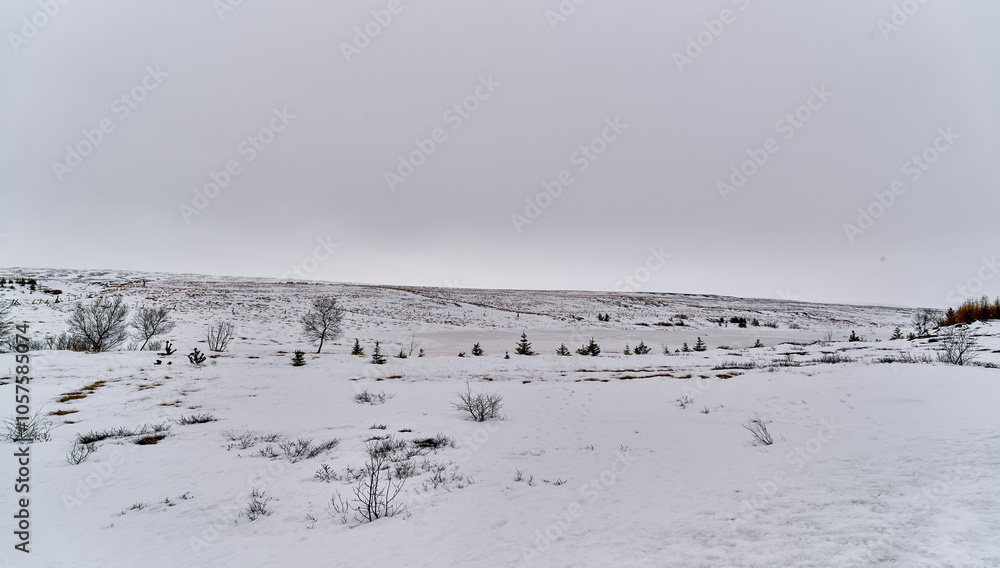 Frozen lake surrounded by snow covered hills on a cloudy winter day Frozen lake surrounded by snow covered hills on a cloudy winter day