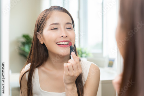 Skin care, beauty cosmetics concept, pretty asian young woman, girl make up face by applying red lipstick, lips balm on her mouth, looking at the mirror at home. Female look with natural fashion style Free Download Skin care, beauty cosmetics concept, pretty asian young woman, girl make up face by applying red lipstick, lips balm on her mouth, looking at the mirror at home. Female look with natural fashion style - GFXLoad