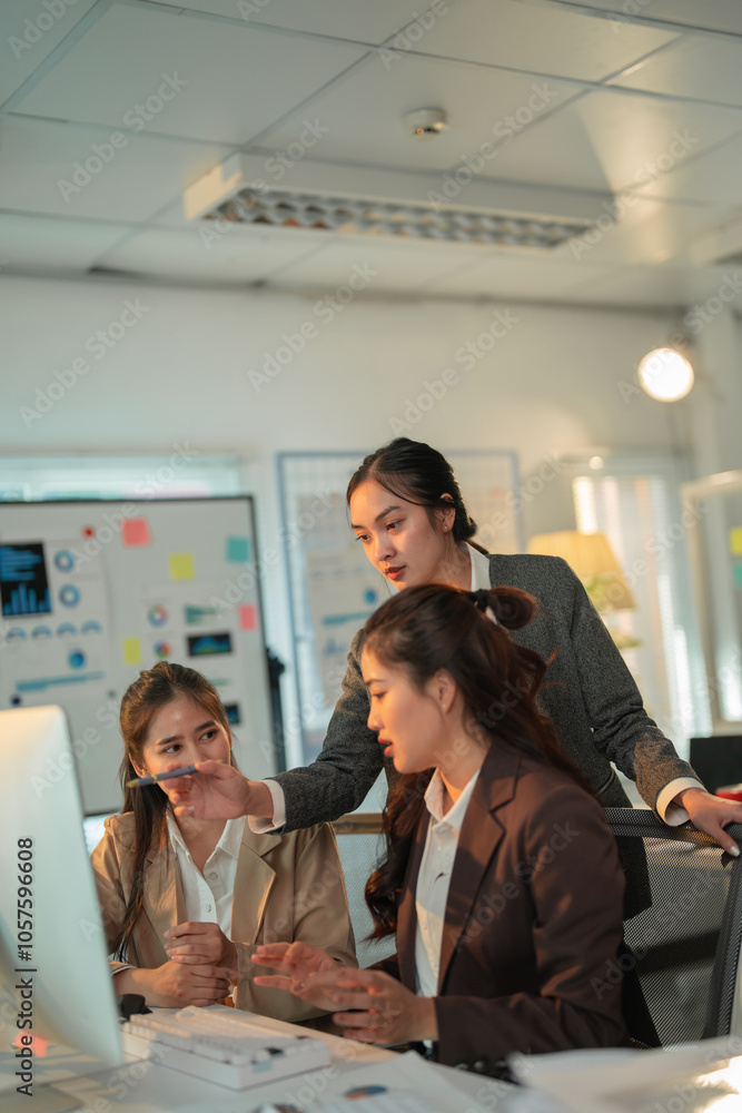 Three asian businesswomen are working together on a computer, discussing a project in a modern office meeting room, collaborating and sharing ideas Three asian businesswomen are working together on a computer, discussing a project in a modern office meeting room, collaborating and sharing ideas