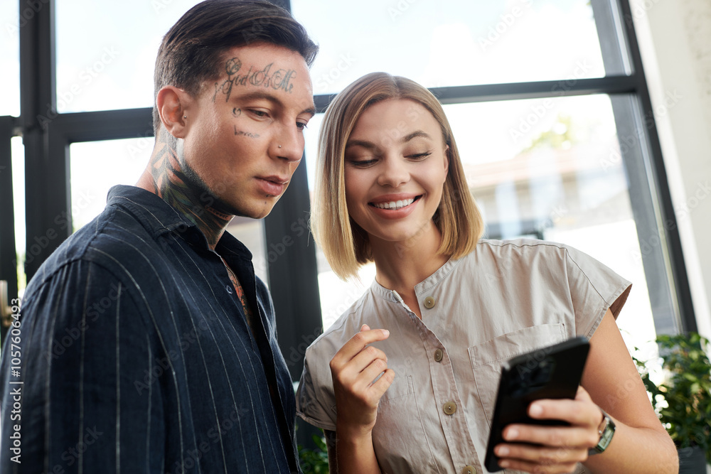 Two colleagues engage with enthusiasm, laughing and discussing on a mobile phone in the office. Two colleagues engage with enthusiasm, laughing and discussing on a mobile phone in the office.