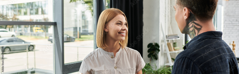 Two coworkers share ideas and smiles while collaborating in a bright office setting. Two coworkers share ideas and smiles while collaborating in a bright office setting.