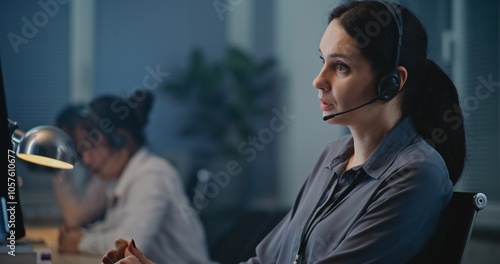 Multiethnic team of helpline operators working in call center of psychological hotline: Caucasian female specialist in headset communicating and supporting person on call. Suicide prevention service.