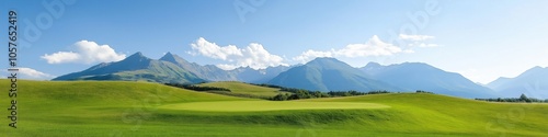 A beautiful mountain range with a clear blue sky. The mountains are covered in green grass and the sky is filled with fluffy white clouds. The scene is peaceful and serene