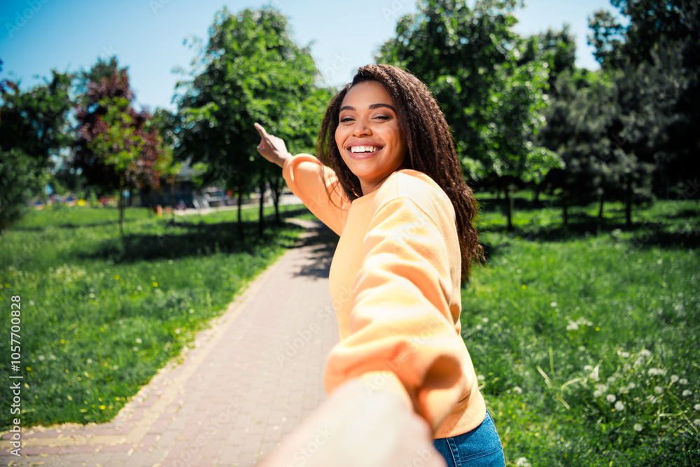 Photo of adorable sweet lady wear orange sweater walking holding boyfriend arm showing route outdoors urban city park Photo of adorable sweet lady wear orange sweater walking holding boyfriend arm showing route outdoors urban city park