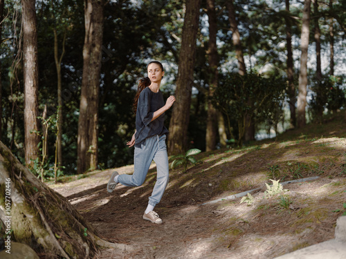 Energetic young woman jogging through a lush forest, dressed in comfortable athletic wear Fitness and nature exploration concept