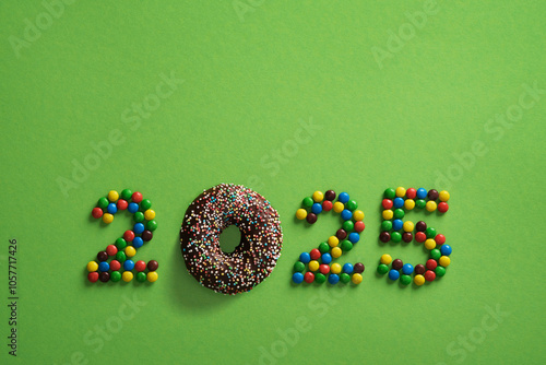 Candy and chocolate donut figures 2025 on green background. New Year concept