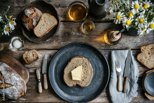 Freshly sliced whole grain bread with oats on a wooden board accompanied by h...