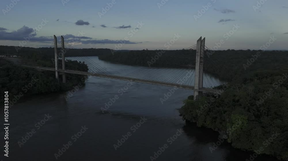 Drone hovers high over river overlooking suspension bridge during sunset Drone hovers high over river overlooking suspension bridge during sunset